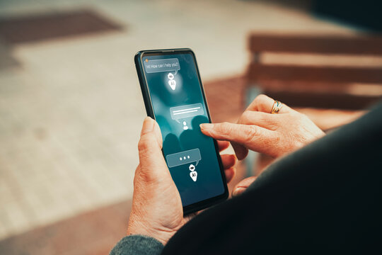 Mature woman chatting with AI chatbot assistant on smartphone screen. Artificial intelligence adoption, virtual assistants, and technology accessibility for older adults.