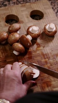 Woman's hands slicing portobello mushrooms on cutting board.