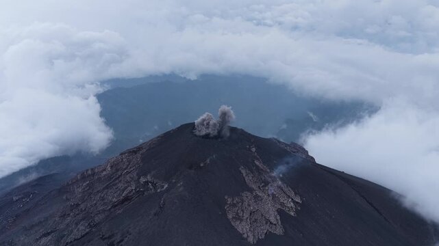 Aerial view of Volcan de Fuego crater with volcanic smoke and surrounding clouds in Yepocapa, Chimaltenango Department, Guatemala.
