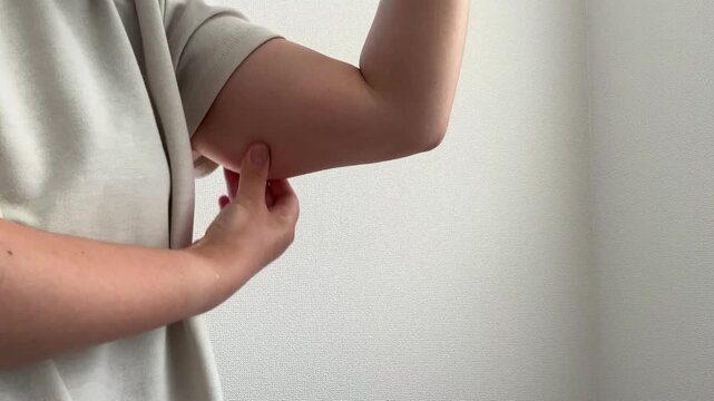 二の腕をつまむ女性