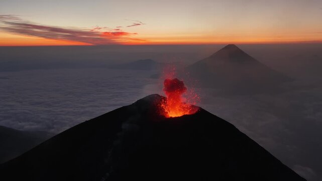 Aerial view of Volcan de Fuego erupting above a sea of clouds during a vibrant sunset in Yepocapa, Chimaltenango, Guatemala.