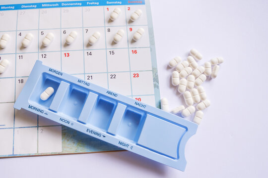 Organized health tracking with dose dispenser and white pills layout on paper calendar for longevity routine, proactive disease prevention, monitoring drug adherence in silver economy, nursing care.