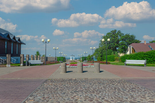 Park promenade flower beds lamp posts benches blue sky sea view sunny day