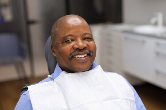 Smiling black male patient relaxing comfortably in dental chair before or after treatment, reflecting positive experiences, preventive care and confidence in oral health