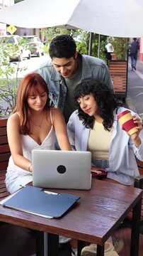 group of latinos young friends using laptop and having fun outdoors in terrace in Mexico Latin America 