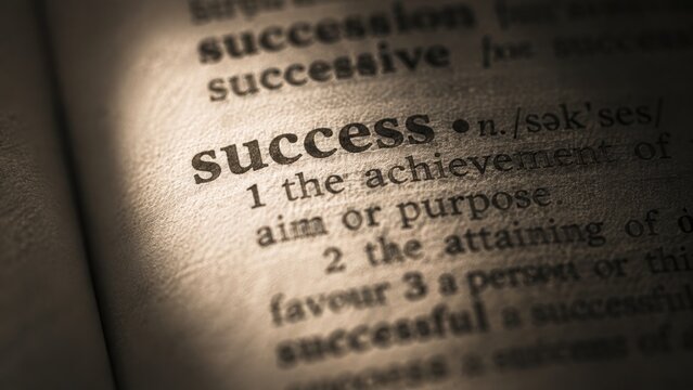 The success definition printed inside an open dictionary book focusing on achievement.