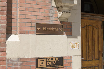 Fototapeta premium historic building and metal plaque signs of Electric Mind (technology consulting) and OLEA DEV (real estate) located at 200 Adelaide St W, Toronto