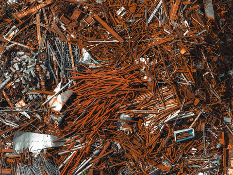 Aerial view of rusty steel scrap, metal beams, and industrial debris piled at a metal recycling yard in Poland.