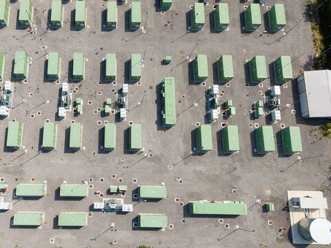Aerial view of the BESS SERRE TAVAZZANO battery energy storage system with rows of green containers and electrical infrastructure on a gravel site in Tavazzano con Villavesco, Lombardy, Italy.