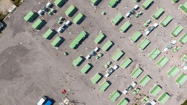 Aerial view of the BESS SERRE TAVAZZANO battery energy storage system featuring rows of green containers on a gravel lot in Tavazzano con Villavesco, Lombardy, Italy.