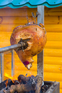 Whole roasted pork on a spit over an open wood fire. Traditional outdoor barbecue with crispy golden skin, rustic cooking and authentic countryside feast.