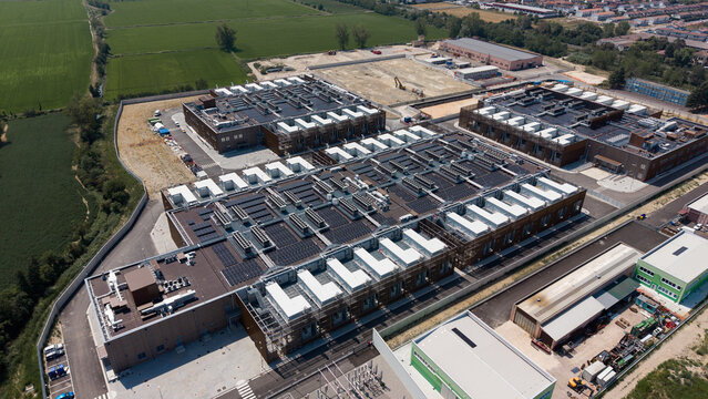 Aerial view of Stack Infrastructure MIL04 Campus featuring modern data center buildings with rooftop cooling units and solar panels in Vellezzo Bellini, Lombardy, Italy.