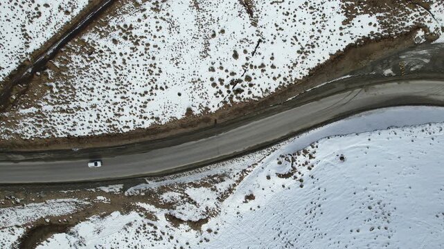 Aerial top view of a car driving in frozen road	