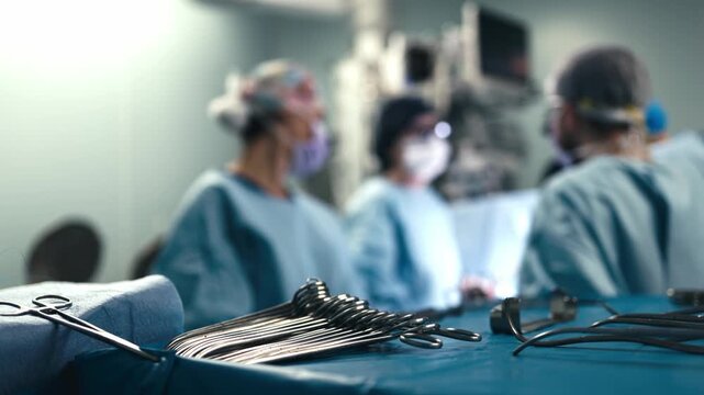 Sterile surgical instruments prepared for use with a surgical team working in the background. Concept modern surgery, medical equipment, sterile environment, professional healthcare and patient care.