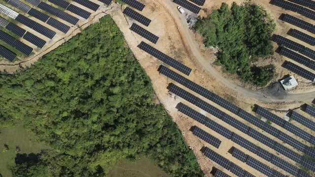 Aerial view of Sikatuna Solar Power Plant with rows of photovoltaic panels installed on cleared land surrounded by lush tropical vegetation in Sikatuna, Central Visayas, Philippines.