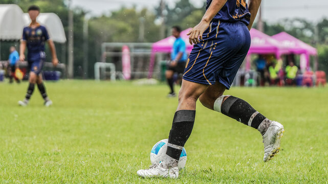 Soccer player controlling the ball during competitive football match on outdoor grass field