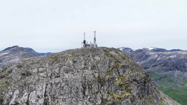 Aerial view of the rocky Trollstigen mountain peak featuring communication towers set against a vast mountainous landscape in Andalsnes, More og Romsdal, Norway.