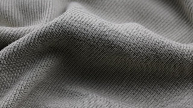 Fabric texture close-up shows folds and patterns of a gray fabric