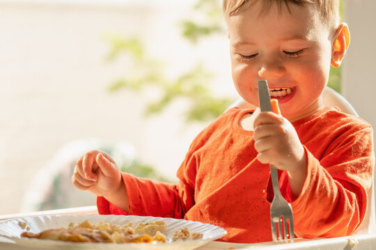 Happy toddler eating homemade cottage cheese crepes during a family breakfast.
