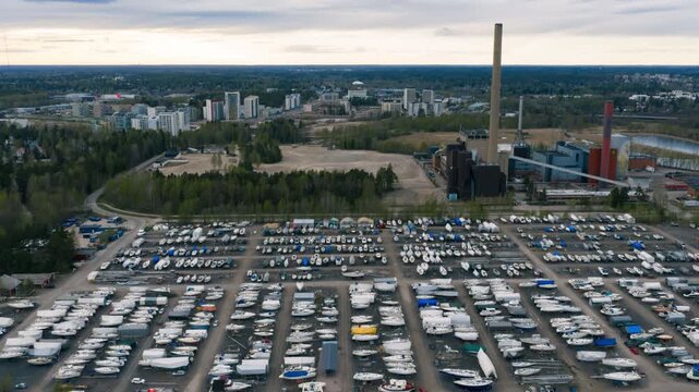 Aerial view of Finno marina with numerous boats in dry storage and docks in the water, with an industrial plant in the background in Espoo, Uusimaa, Finland.