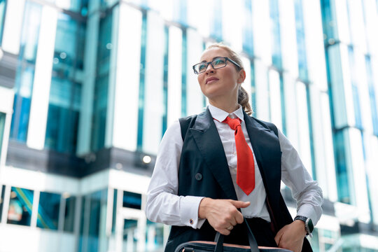 Business woman stands outside modern building with confidence and purpose on a sunny day