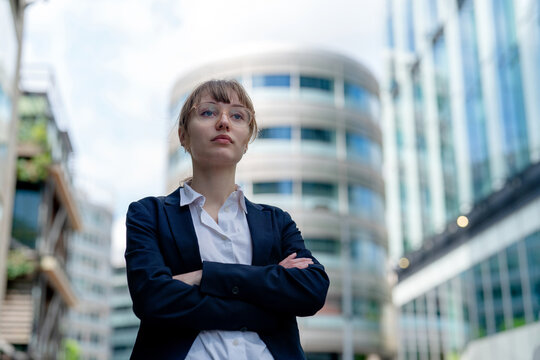 Business person stands confidently in a modern urban setting with tall buildings in the background during the daytime