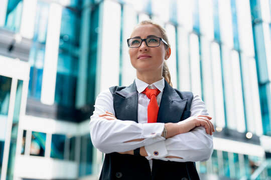 Businesswoman stands confidently outside a modern office building during the day