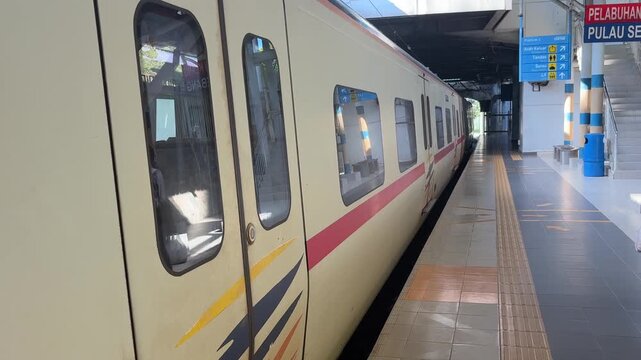 Malaysian KTM Komuter electric train arriving at the station platform, public transportation.