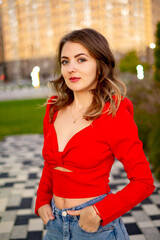 a beautiful young girl walking in the summer in a red sweater, a girl in the park in the summer, a...