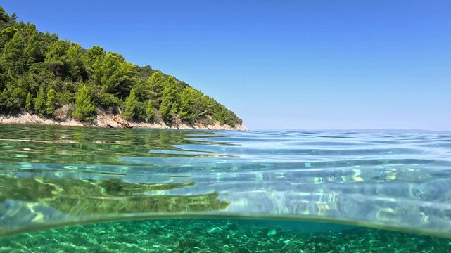 Crystal clear sea water splits the frame near Korcula island in Croatia. Sunlight refracts through turquoise ocean surface on sunny day. Picturesque split shot of adriatic sea in Croatia