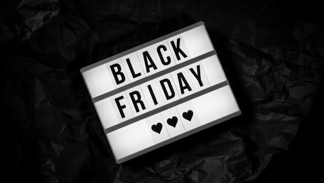 Black friday text on illuminated light box with three hearts