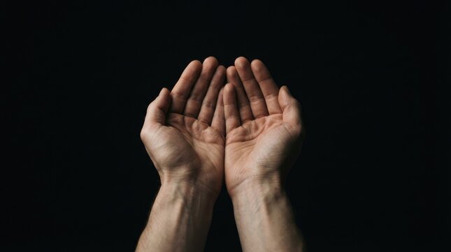 Cupped human hands held together against a dark background representing hope and support for world mental health day to raise awareness for emotional wellbeing issues