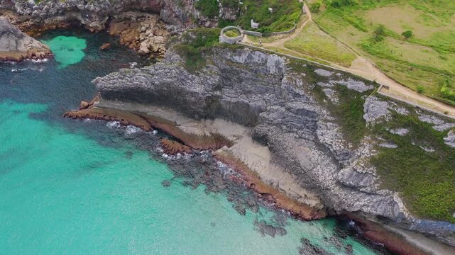 Aerial View of the Sea Cliffs and Green Grass Footpath Along Paseo de San Pedro Hiking Trail in Llanes, Asturias, Northern Spain