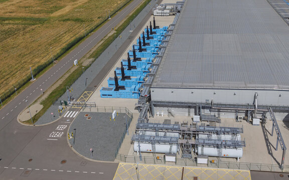 Aerial view of the Google data center Agriport A7 with rows of blue power generators and industrial infrastructure near paved roads in Middenmeer, North Holland, Netherlands.
