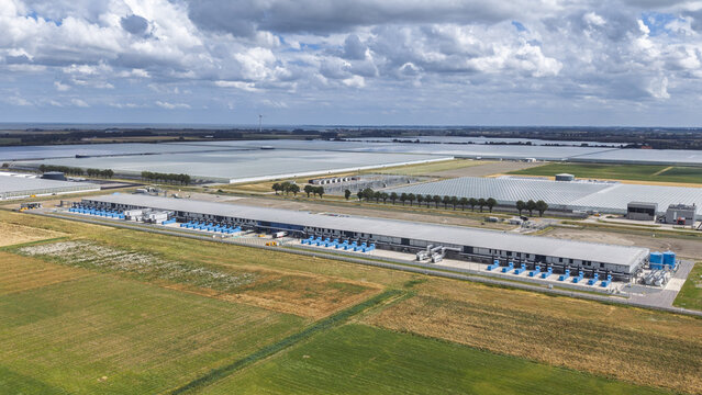 Aerial view of Google data center Agriport A7 surrounded by vast agricultural fields and greenhouse complexes under a cloudy sky in Middenmeer, North Holland, Netherlands.
