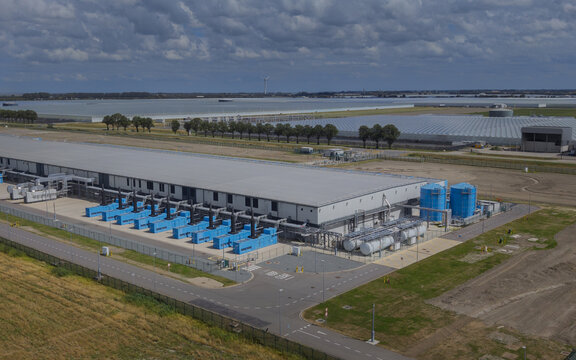 Aerial view of Google data center Agriport A7 with industrial buildings, blue cooling units, and storage tanks near agricultural fields in Middenmeer, North Holland, Netherlands.