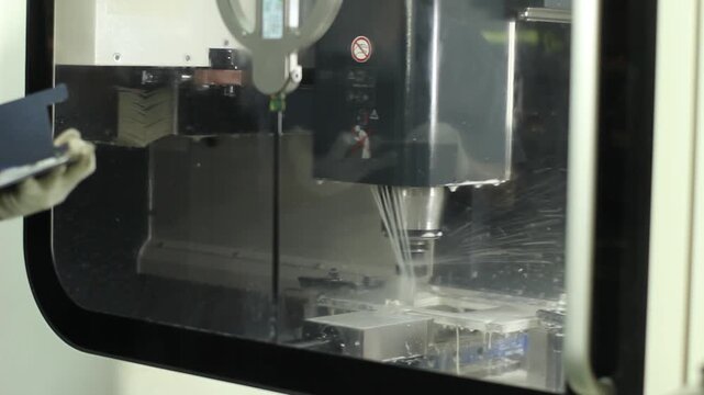 CNC milling machine cutting metal with coolant spray in a workshop