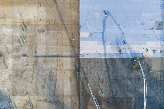 Aerial view of construction workers pouring concrete on a large slab with heavy machinery and reinforcement mesh visible in Zemun, Vojvodina, Serbia.