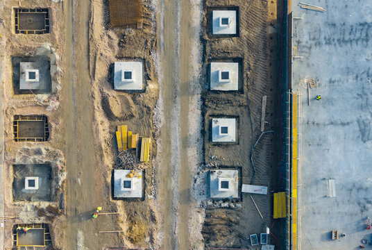 Aerial view of an industrial construction site featuring concrete foundation bases, heavy machinery access paths, and workers on site in Zemun, Vojvodina, Serbia.
