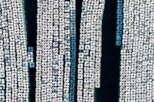 Aerial view of hundreds of green steel drums stacked in an industrial storage yard, forming a striking geometric pattern in Zemun, Vojvodina, Serbia.