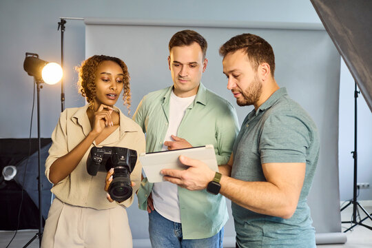 Photographers team in studio review images. Tablet and camera support discussion, task alignment, and collaboration for an efficient workflow. Clear teamwork and creative collaboration concept.