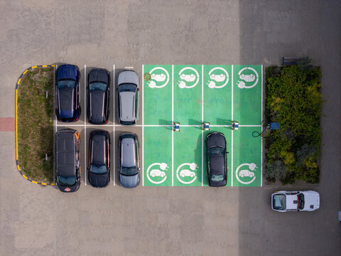 Aerial view of electric vehicle charging stations in a parking lot with several parked cars in Gdansk, Poland.