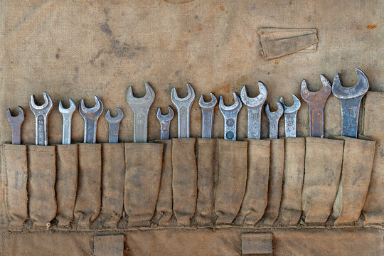 Vintage open end wrench set in old canvas tool roll. Complete set retro steel open-end wrenches neatly organized in dirty canvas tool roll pouch. Concept mechanic work, retro garage and hand tools