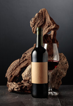 Red wine with old snag and a piece of granite rock on a black background.