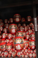 Fototapeta premium Stack of Daruma Dolls: A large collection of red Daruma dolls, symbols of perseverance and good luck, are neatly stacked and displayed, evoking a sense of tradition and aspiration.