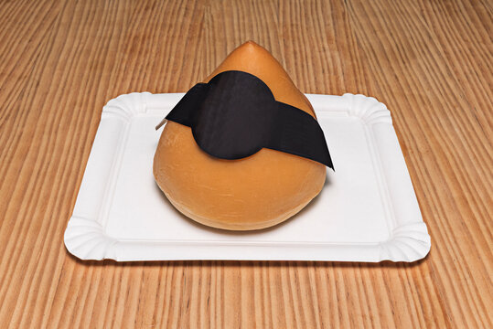 Distinctive breast-shaped Galician San Sim&oacute;n cheese with black label wrap, displayed on paper tray over wood