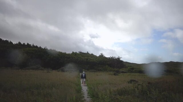 Hirtshals, Denmark A man walks on a boardwalk through the dunes on a hiking path in the rain. 