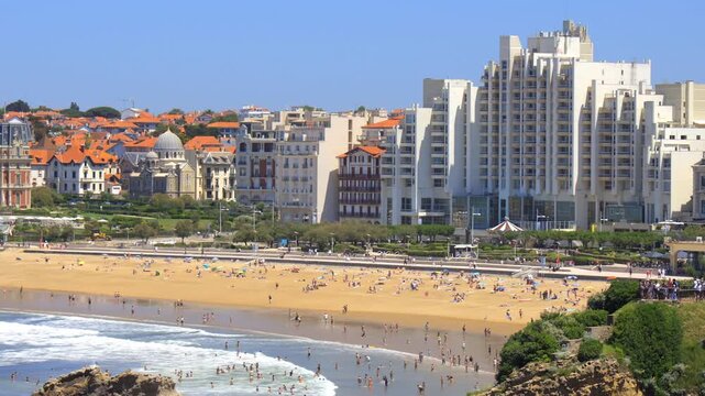 High-angle view showing beachgoers sunbathing on the sands of Grande Plage with iconic seaside architecture in the background in Biarritz, France