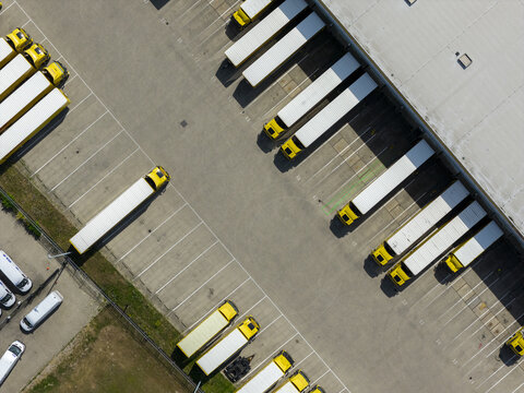 Aerial view of the DHL logistics and mail delivery facility with numerous yellow trucks and trailers parked at loading bays in Zwolle, Overijssel, Netherlands.