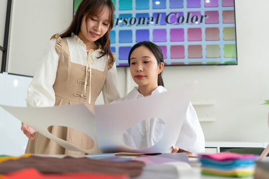 Stylist consulting client with color palettes in creative studio
